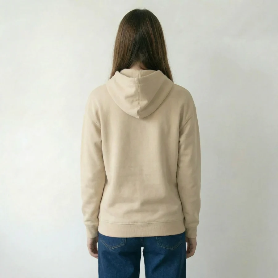 Mulher com casaco de capuz bege e jeans azuis virada para trás.