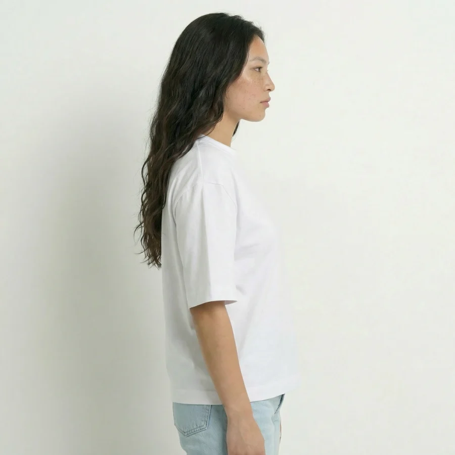 Mulher de lado com T-shirt Over Boxy branca e jeans claros.