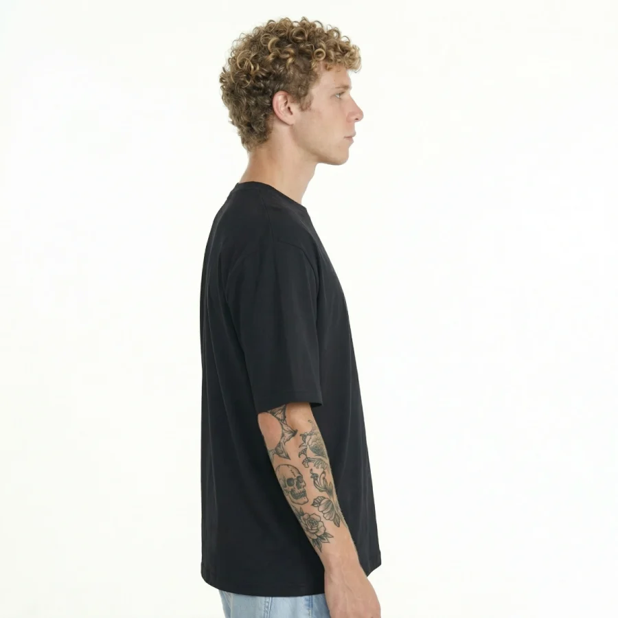 Homem com cabelo encaracolado e tatuagens, usando T-Shirt Urban Oversize preto.