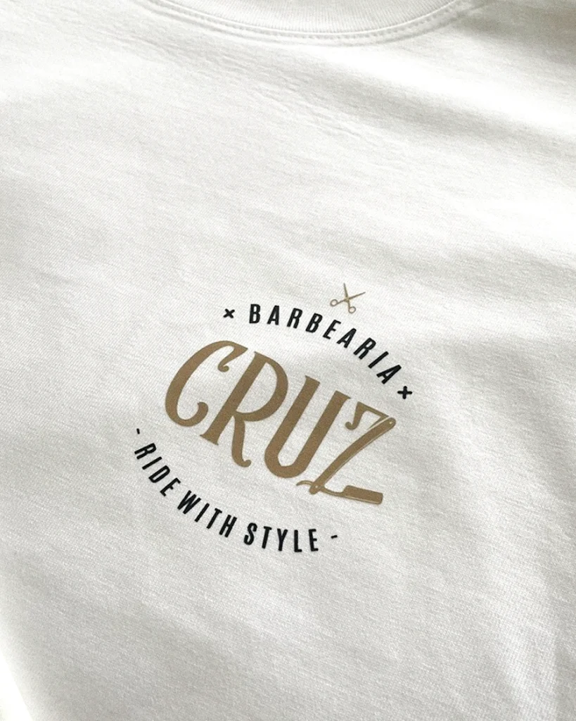 Camisola branca com logótipo dourado e preto Barbearia Cruz e Ride with Style.