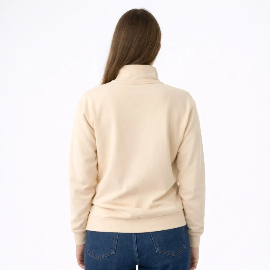 Mulher com o verso de um Half Zip Sweater bege e calças de ganga.