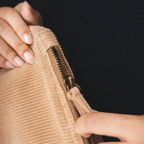 Beige fabric pouch with a zipper.