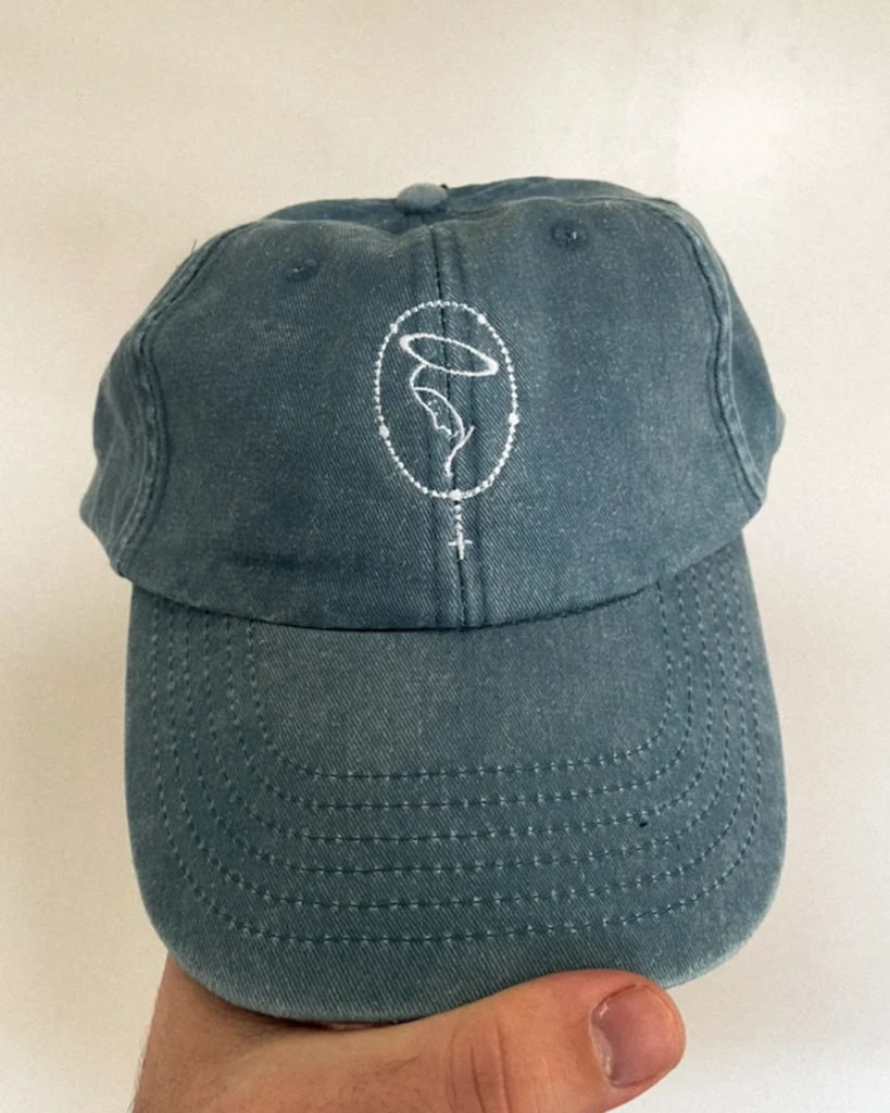 Chapéu de pala com bordado de uma silhueta feminina com auréola e crucifixo.