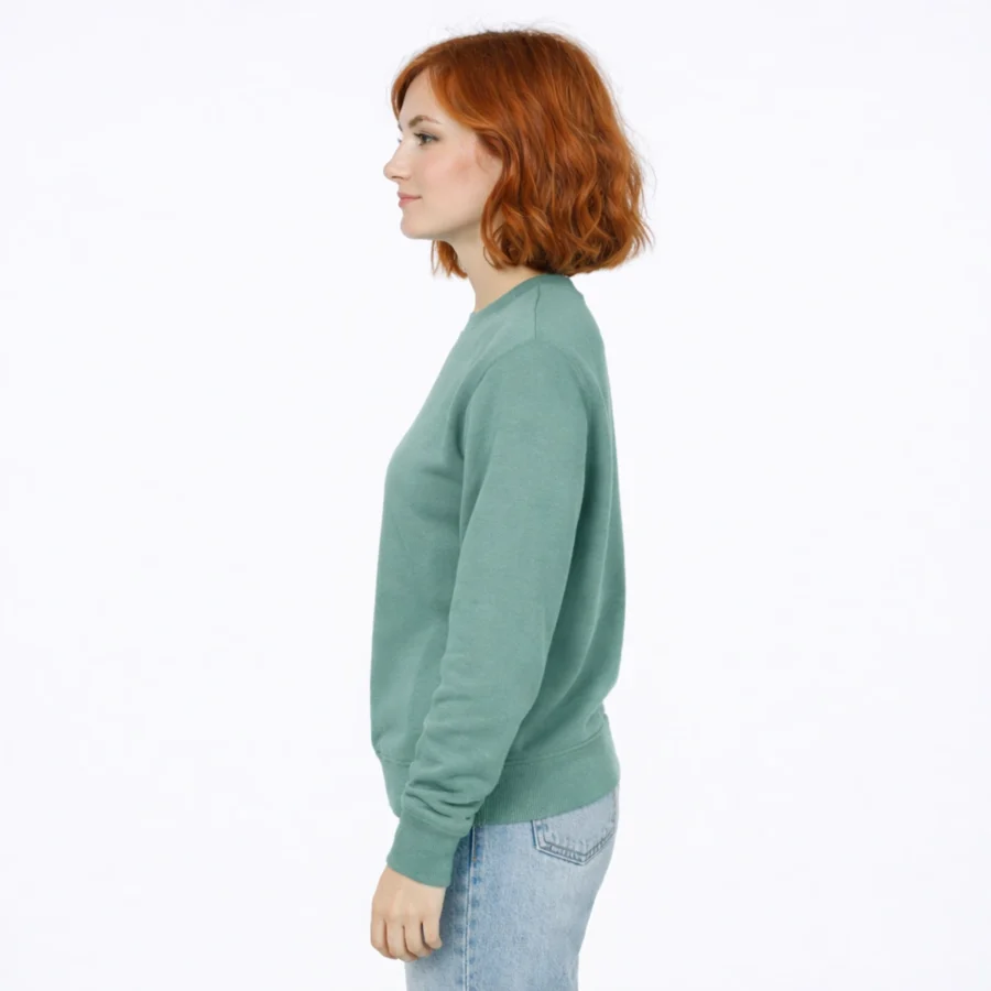 Mulher de cabelos ruivos usando sweatshirt verde e jeans claros.