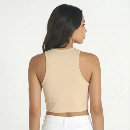 Woman with her back turned wearing a beige crop top and white pants.