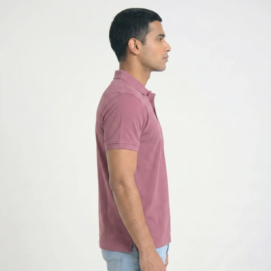 Homem de lado, a usar polo rosa curto.