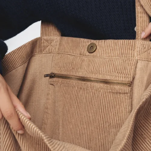 Detail of a light pink bag pocket with drawstrings and a zipper.
