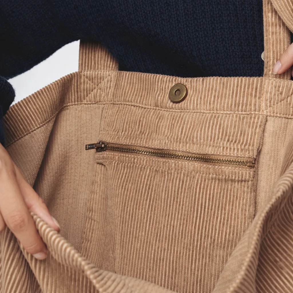 Detalhe de bolso de saco em cor-de-rosa claro com cordões e fecho éclair.